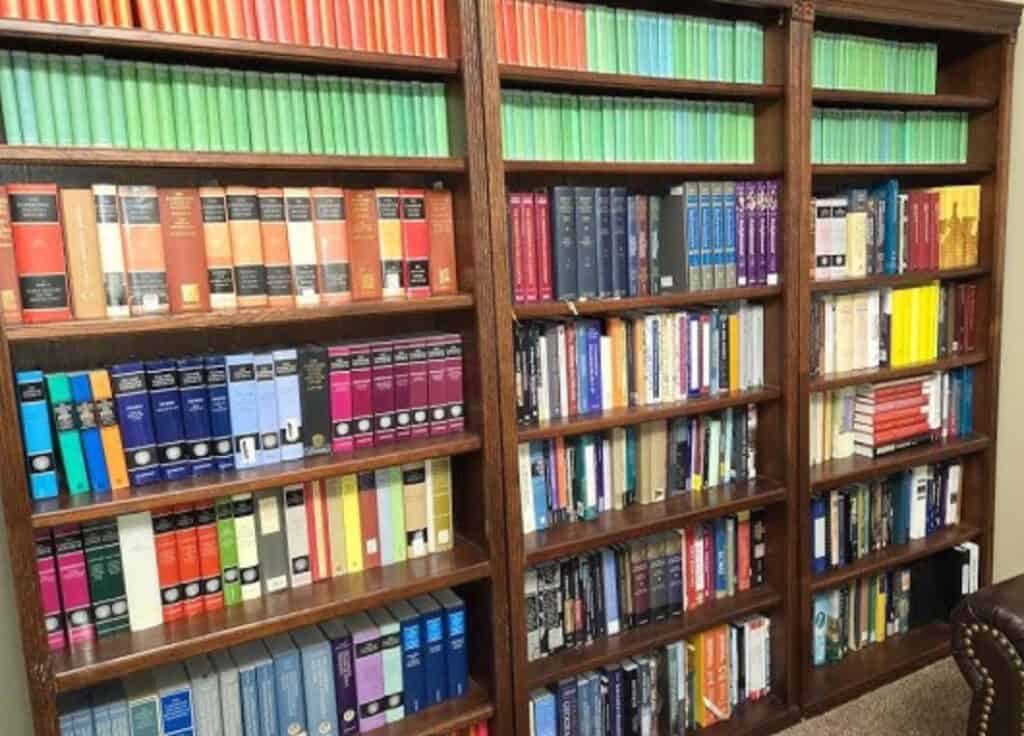 Wooden bookshelves filled with commentaries, theology books, and various interpretations of Scripture, all neatly arranged in rows across a range of genres and sizes.
